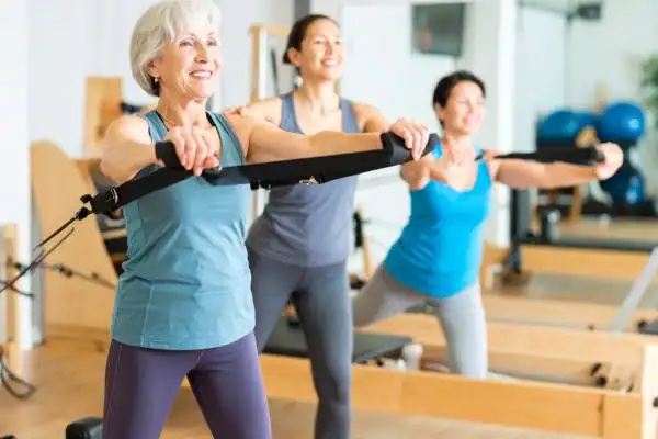 Toning Arms After 60: Empowering Womens Fitness Through Effective Weight Training 2 older woman doing weight training Greenock and resistance in the gym to tone upper arms