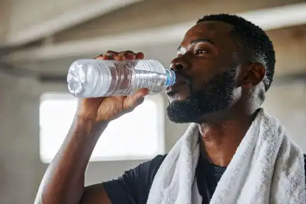 Image of man drinking water to improve hydration Greenock  after work out.